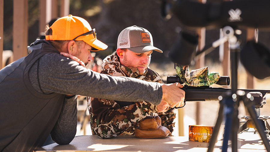 Two men engaged in firearms safety training at a shooting range.